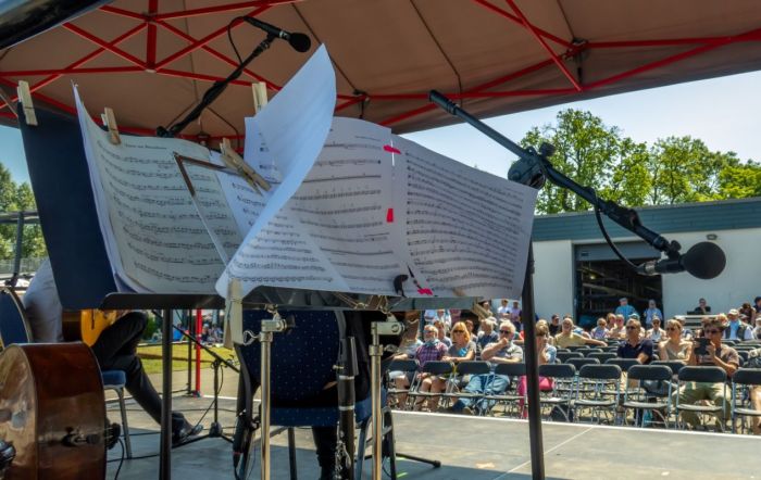 Notenblätter auf einer Bühne flattern im Wind.
