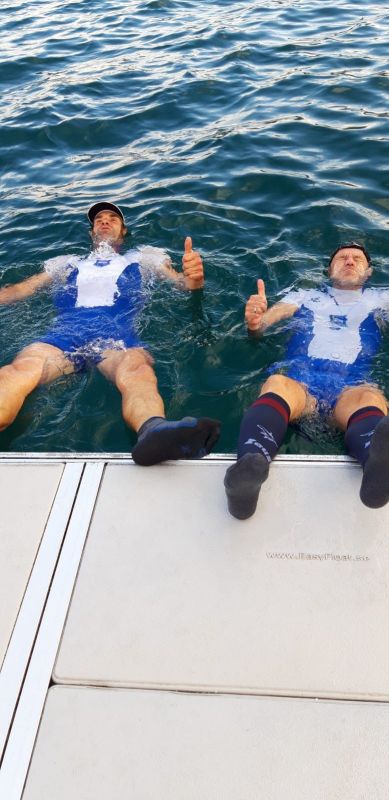 Ruderer liegen entspannt am Steg im Wasser